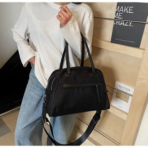 Dettaglio borsa da viaggio in nylon nero con manici in pelle e tracolla lunga regolabile