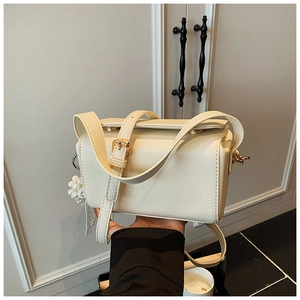 Detail of cream-colored pebble leather crossbody bag with elegant pearl charm accessory