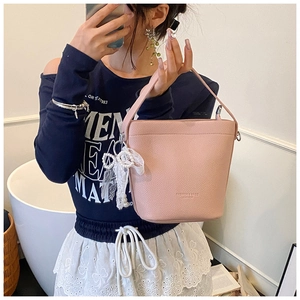 Dettaglio di una borsa a secchiello rosa in pelle martellata con fiocco e perla