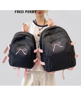 Détail de deux sacs à dos en nylon noir avec broderie nœud rose et bretelles roses