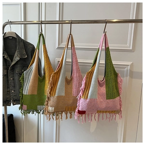 Detail of bohemian knit hobo bags featuring colorful stripes and side fringe accents