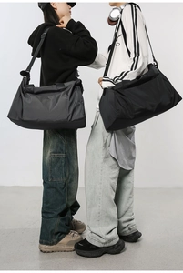 Deux modèles portant de grands sacs de voyage en nylon noir et gris foncé avec sangles