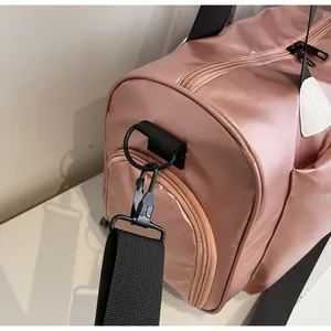 Detalle de los ganchos de metal negro y el anillo en D en la bolsa de viaje rosa