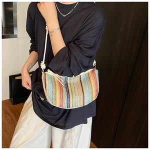 Detailed macro view of woven rainbow stripe bag with white shoulder strap and tassel