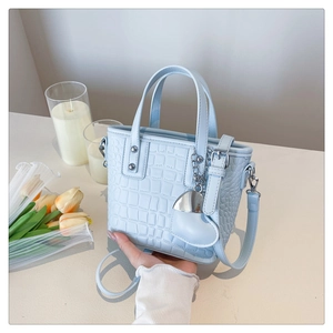 Macro detail of light blue crocodile pattern faux leather bucket bag with silver hardware