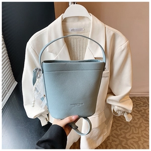 Dettaglio borsa a secchiello in pelle celeste con pendente di perle e pizzo