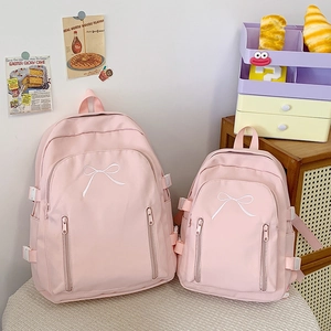 Détail de sacs à dos en toile rose en tailles L et S avec broderie de nœuds blancs élégants