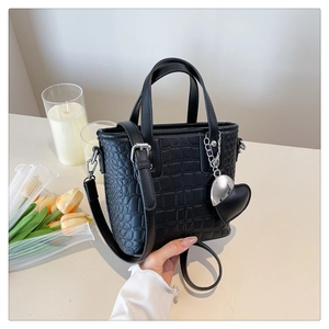 Detail of black crocodile texture bucket bag with silver hardware and heart charm