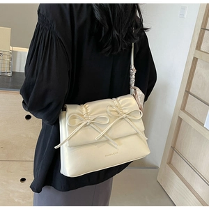Détail du sac crème style ballet avec volants, nœuds et foulard rose à cœurs en soie