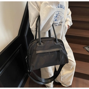 Detail of minimalist black nylon tote bag with leather straps on a wooden staircase