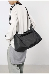 Vue arrière d'un sac bandoulière en nylon noir porté par un mannequin en studio