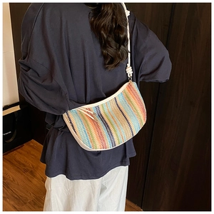 Detail of colorful knitted hobo bag showing vibrant vertical stripes and knotted white strap