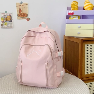 Détail du sac à dos rose avec broderie nœud et plusieurs poches zippées pratiques