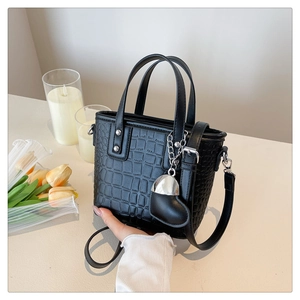 Detail of black crocodile pattern crossbody bucket bag with heart charm and strap