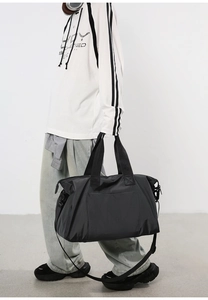 Détail d'un sac de voyage noir multifonction avec poignées renforcées et vue de côté