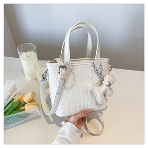 Detail of white crocodile pattern bucket bag with detachable strap and cute pendant charm
