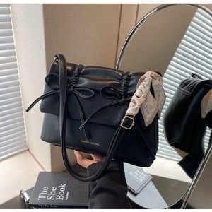 Détail du sac plissé noir avec nœud décoratif et foulard en soie imprimé de cœurs