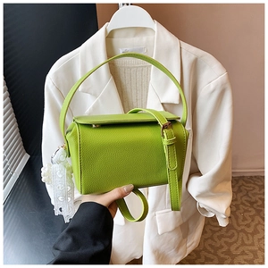Detail of bright green pebble leather handbag with pearl lace charm and top handle