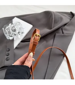 Détail de la bandoulière en cuir marron avec texture litchi et boucle dorée chic