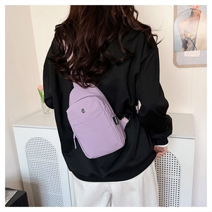 Detail of light purple nylon chest bag with adjustable black strap on a model