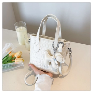 Detail of off-white crocodile embossed bucket bag with dog charm and silver chain strap