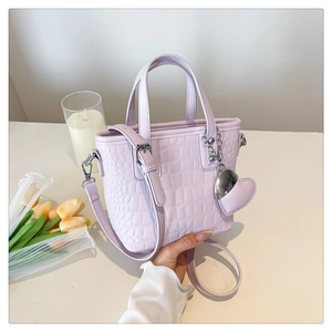 Detail of lilac crocodile pattern crossbody bucket bag with heart pendant accessory