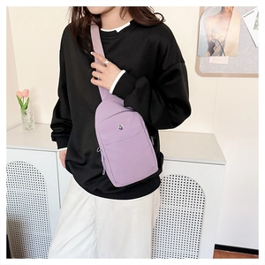 Light purple nylon crossbody bag worn by model in a modern minimalist indoor setting