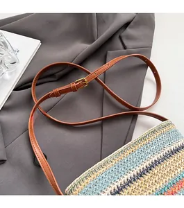 Détail d'une bandoulière réglable en similicuir marron sur un sac seau tissé coloré