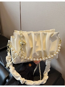 Chic beige pleated cloud bag with pearl chain and thick shoulder strap in studio setting