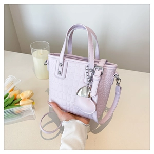Detail view of light purple crocodile pattern handbag with heart metal charm and strap