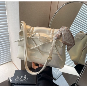 Détail du sac à nœud crème avec écharpe à cœurs et finitions en cuir plissé élégant