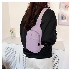 Light purple nylon crossbody chest bag shown on model in a cozy lifestyle setting