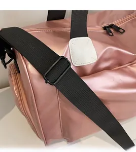 Detalle de la bolsa de viaje oro rosa con correa de hombro negra ancha y ajustable