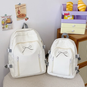 Comparaison détaillée de deux tailles pour le sac à dos blanc avec nœud décoratif