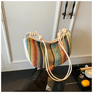Detail of colorful woven straw bag featuring white leather knotted strap and vibrant textures