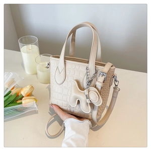 Detail of cream crocodile embossed bucket bag with puppy charm and silver hardware