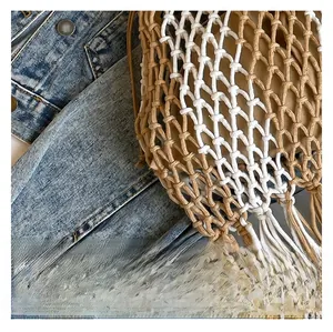 Close-up of hand-woven hollow tote bag with long tassels and beige-white cotton texture