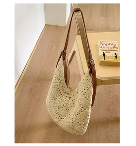 Detail of beige crochet shoulder bag with brown leather strap hanging on a wooden chair
