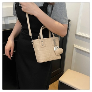 Close-up of beige crocodile pattern texture and heart charm on mini bucket bag