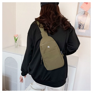Rear view of model wearing a military green nylon crossbody bag with adjustable strap