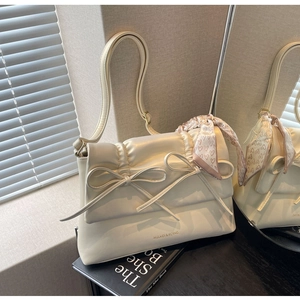 Détail du sac à bandoulière crème avec nœuds et foulard décoratif en cuir plissé élégant