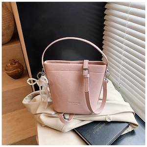 Dettaglio borsa a secchiello in pelle rosa con fiocco di perle e testo dorato