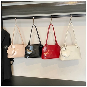 Détail de sacs seaux en cuir verni brillant avec breloques cœur suspendus sur un support
