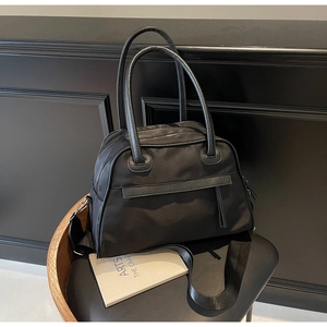 Dettaglio borsa da viaggio nera in nylon con finiture in pelle su sedia da studio