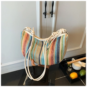 Close-up of rainbow woven half-moon bag featuring white shoulder strap and knotted detail