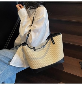 Close-up of beige woven tote bag with contrast black leather trim and metal hardware detail