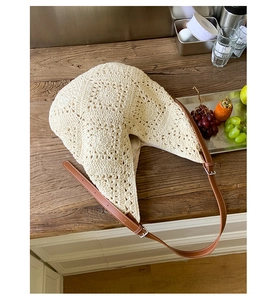 Detail of beige crochet bag featuring intricate knit patterns and brown leather strap