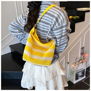 Model view showing the large yellow and beige striped woven hobo tote bag on shoulder