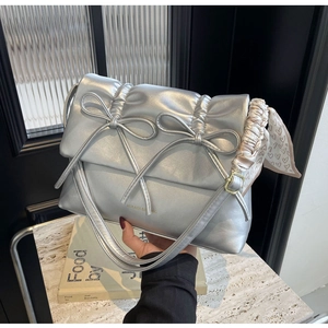 Détail du sac à main argenté métallisé avec nœuds et foulard en soie à motifs