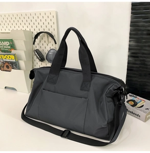 Détail du sac de voyage gris foncé montrant les poignées et la bandoulière réglable